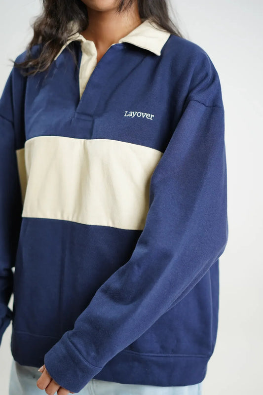 Navy and beige color-blocked sweater with 'Layover' text on a plain background