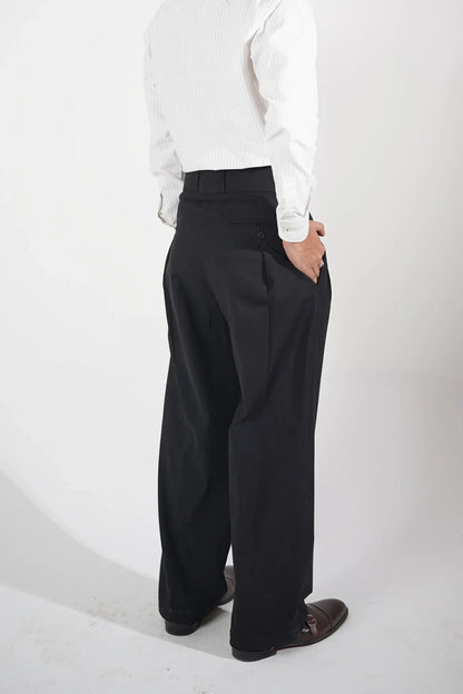 A man wearing a white long-sleeve button-up shirt and black trousers, photographed from a high-angle perspective against a plain white studio background.