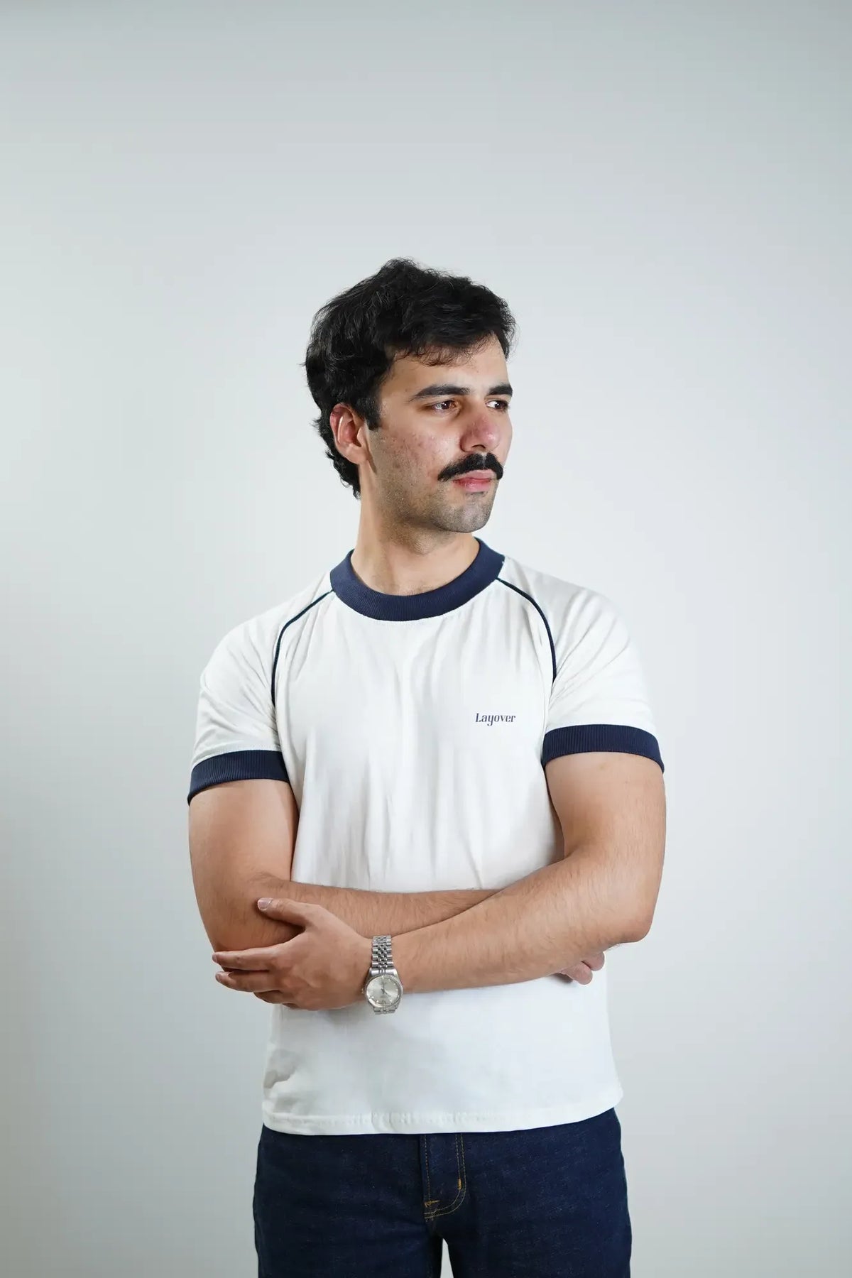 Man wearing a white t-shirt with navy accents and 'Layover' text on a plain background