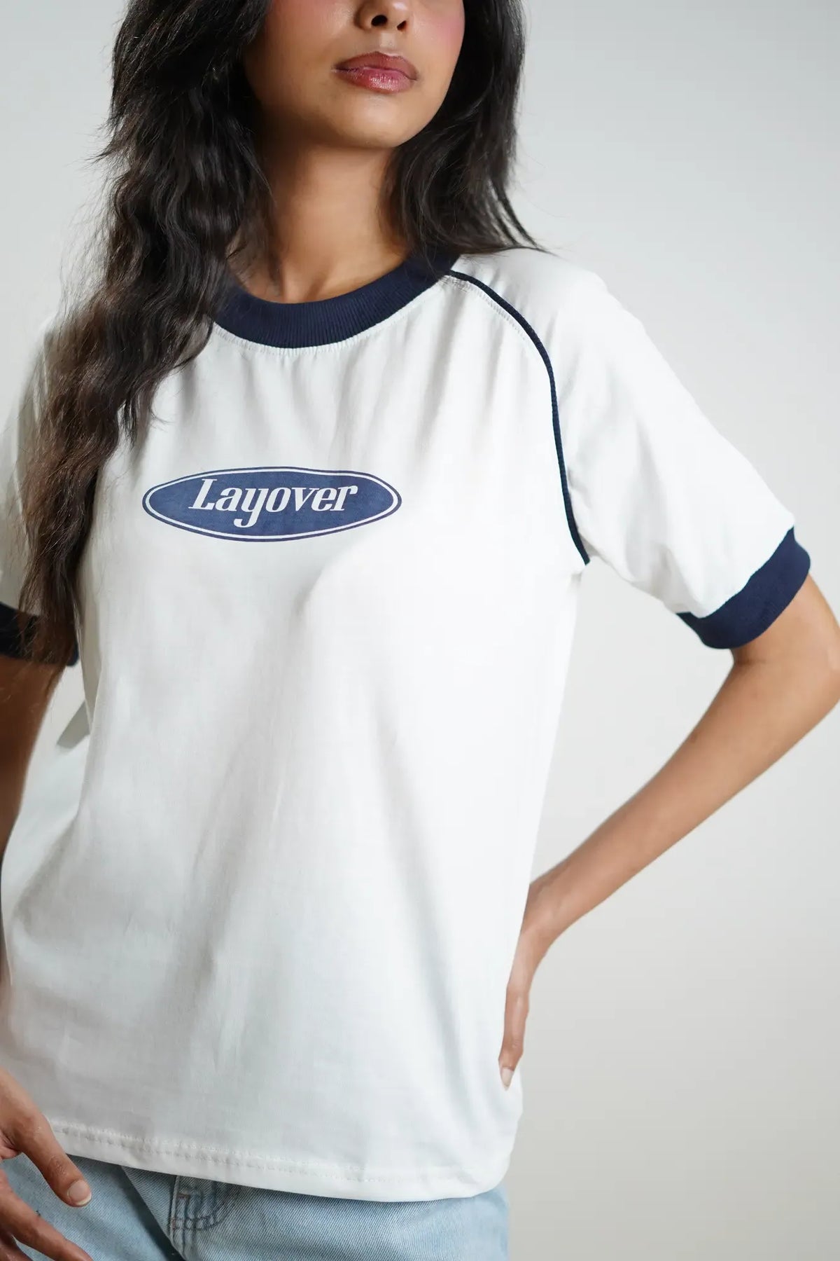 Person wearing a white t-shirt with 'Layover' logo on a plain background