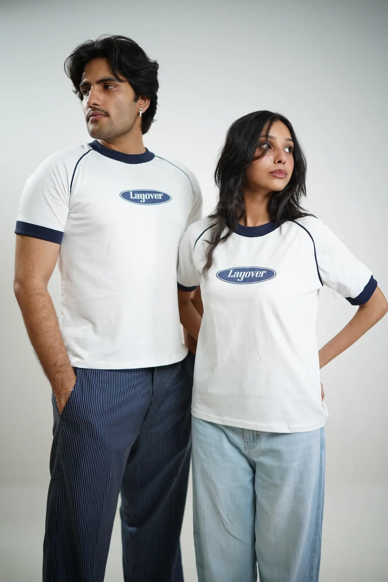 Two people wearing white t-shirts with 'Layover' logo on a plain white background