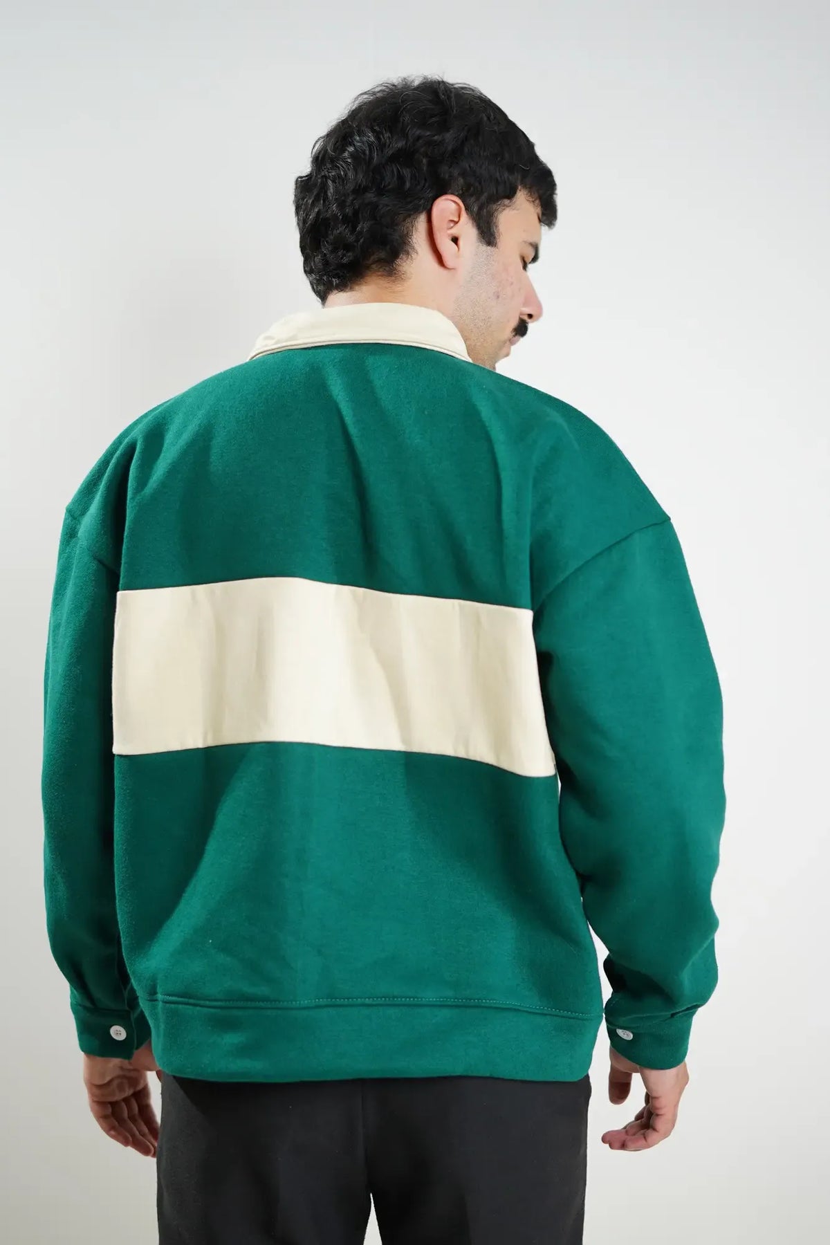 Person wearing a green and beige striped sweater against a plain background