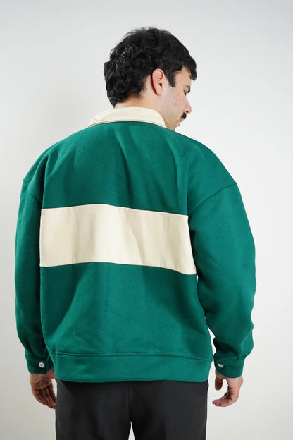 Person wearing a green and beige striped sweater against a plain background